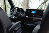 Modern RV rental interior: driver's cockpit with steering wheel, digital dashboard, and infotainment screen. Ready for adventure!