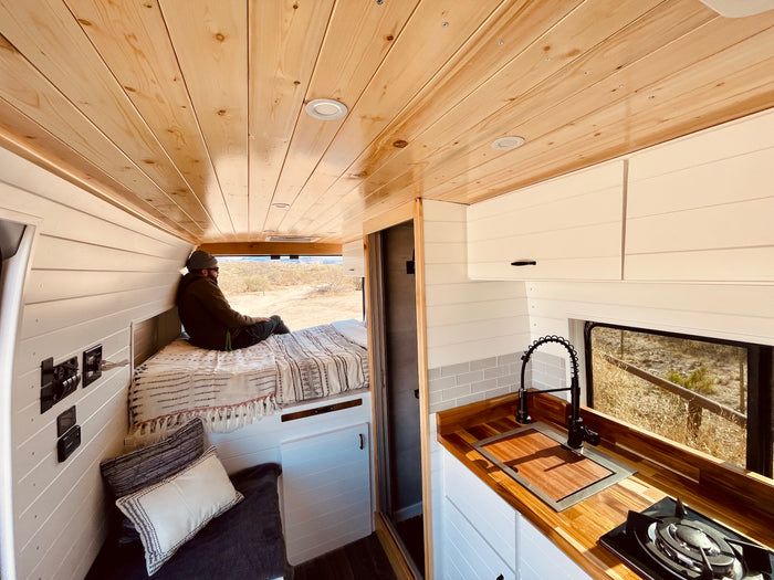 Spacious & cozy rv rental interior with wooden ceilings, kitchen, and bed, perfect for van life adventures.