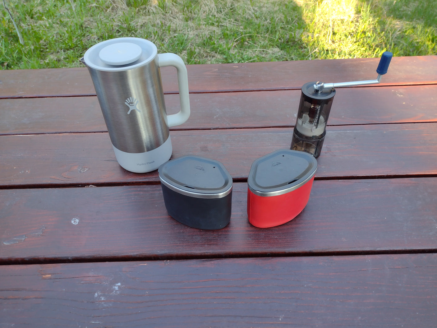 Coffee & camping essentials for your RV rental: Hydro Flask, GSI grinder, MSR containers on a picnic table.