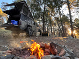 Overlanding setup: Jeep Gladiator with rooftop tent, campfire. A perfect RV rental alternative for forest adventures.