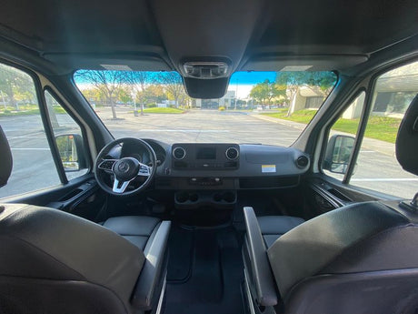 Inside a spacious Mercedes RV rental. View of the dashboard, steering wheel, and front seats from the rear.