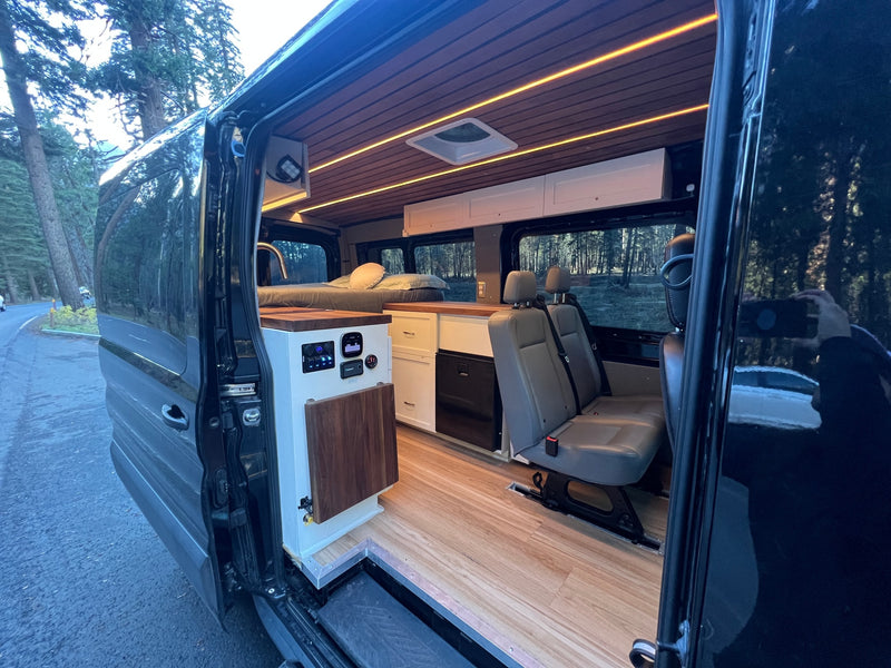 Step into a modern camper van interior, ready for your next RV rental adventure. Features a bed, kitchen, and passenger seats. — photo 17