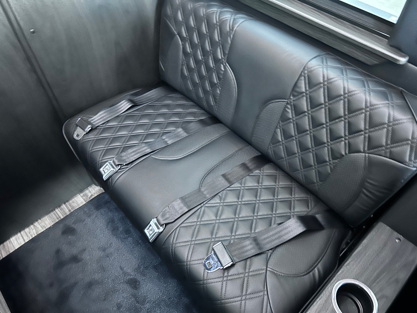 RV rental interior: luxurious quilted bench seat with three seat belts and a cup holder.