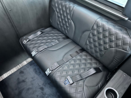 RV rental interior: luxurious quilted bench seat with three seat belts and a cup holder.