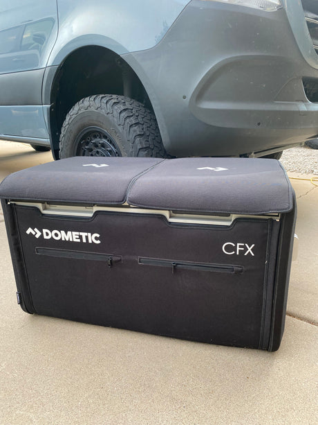 Black Dometic portable fridge (CFX) in front of an off-road RV rental van, ready for adventure.
