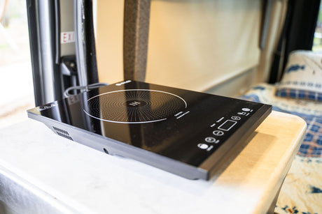 A black portable induction cooktop is set up on a counter within this RV rental, ready for easy travel cooking.