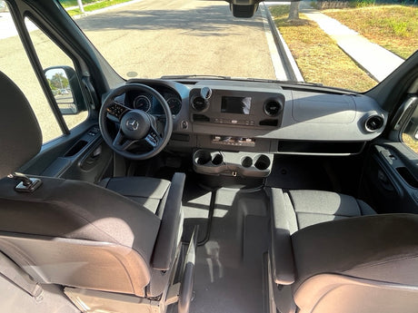 View into an rv rental van's cockpit, showing Mercedes-Benz steering wheel, dashboard, and spacious front area.