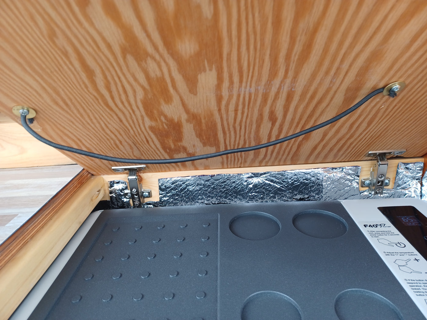 RV rental: Inside a camper, a wood-covered F40 portable cooler/fridge with insulation & control panel. Temp visible. — photo 8