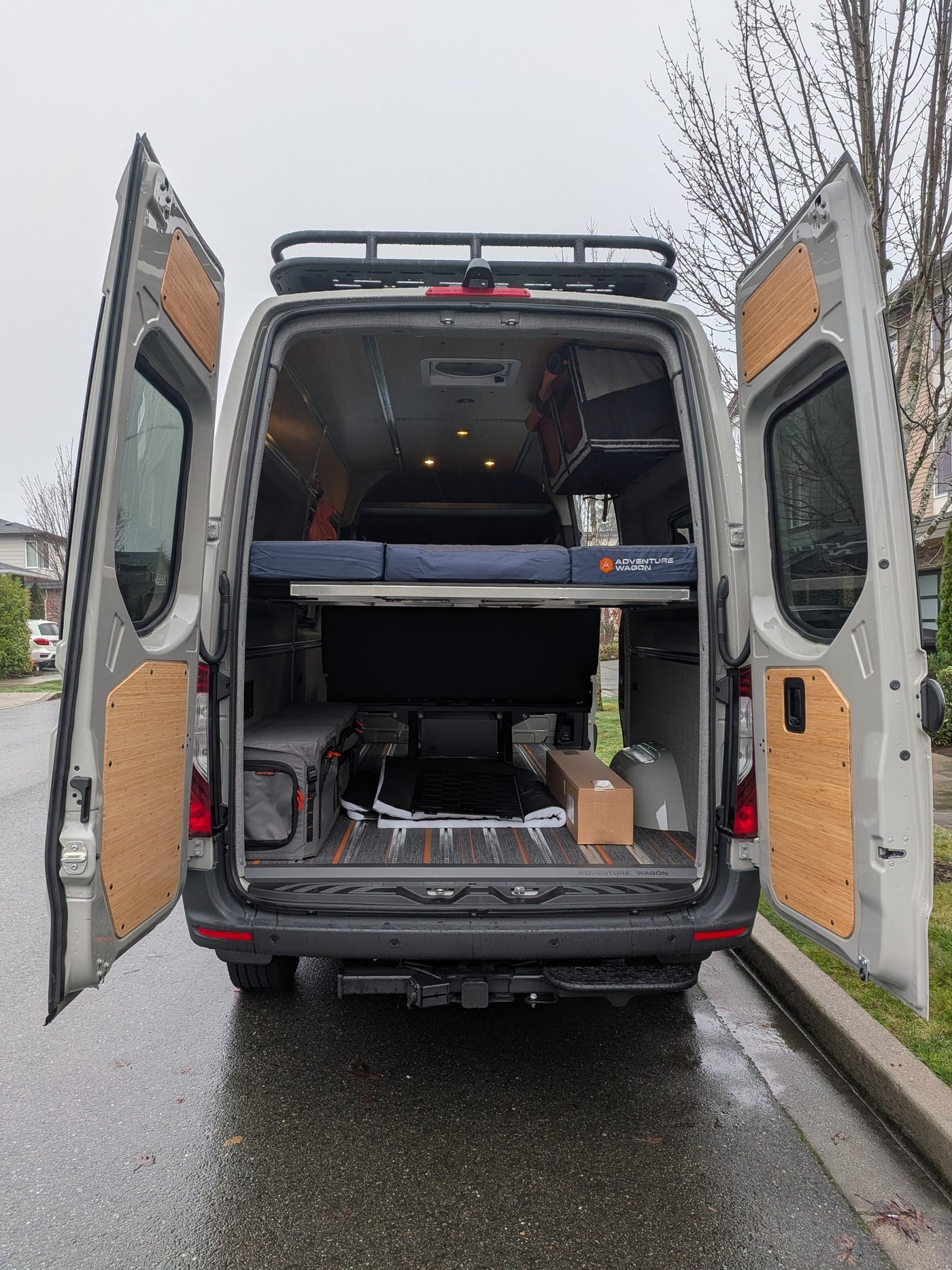 This custom camper van conversion is ideal for RV rental adventures, featuring an open rear with bed, storage, and roof rack. — photo 4