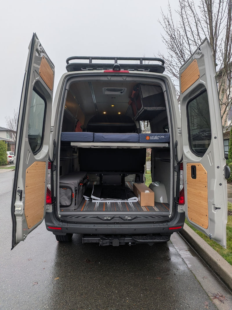 This custom camper van conversion is ideal for RV rental adventures, featuring an open rear with bed, storage, and roof rack. — photo 4