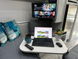 Cozy RV rental interior with a TV showing Netflix, a laptop browsing national parks, and comfortable seating.