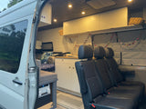 RV rental: Interior view of a custom camper van with a kitchen, comfortable seating, and ambient lighting.