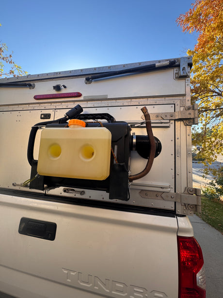 White Tundra truck camper with external diesel heater & tank, ready for cozy RV rental adventures.