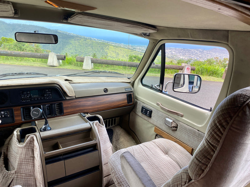 Inside a classic rv rental: a detailed view of the Dodge van's dashboard and comfy interior, overlooking a stunning coastal city. — photo 8