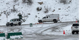 Snowy mountain parking: Jeep, pickup with camper, SUV, & "Lot Full" sign. Plan your rv rental winter adventure.