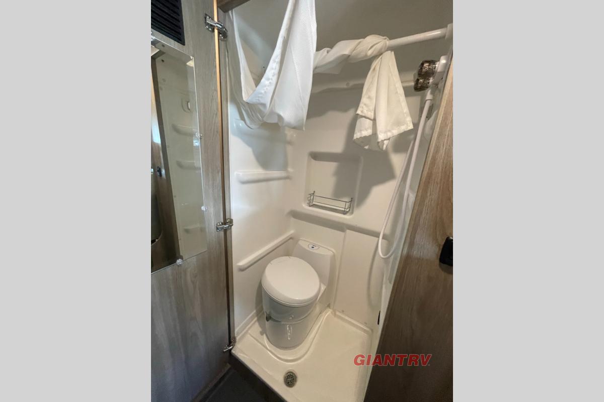 RV rental: This RV's compact bathroom includes a shower, toilet, and mirror on the left wall.