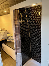 RV rental interior: cozy bed & stylish hexagon-tiled shower in a compact camper van.