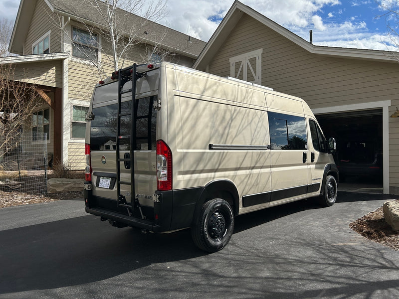 Explore this spacious RV rental! A beige campervan with a rear ladder is parked in a sunlit driveway by a modern home. — photo 1