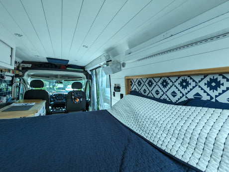 Explore this cozy RV rental interior: a comfy bed, modern kitchen, and driver's area for adventurous travel.