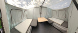 This RV rental's pop-up camper interior features bench beds, a center table, and light tent-style walls.
