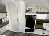 This rv rental offers a comfortable interior with bunk beds, a fridge, AC, storage, and a dining nook.