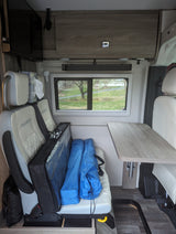 This RV rental interior features swiveling front seats, a compact dining table, and smart storage for a camper van adventure.