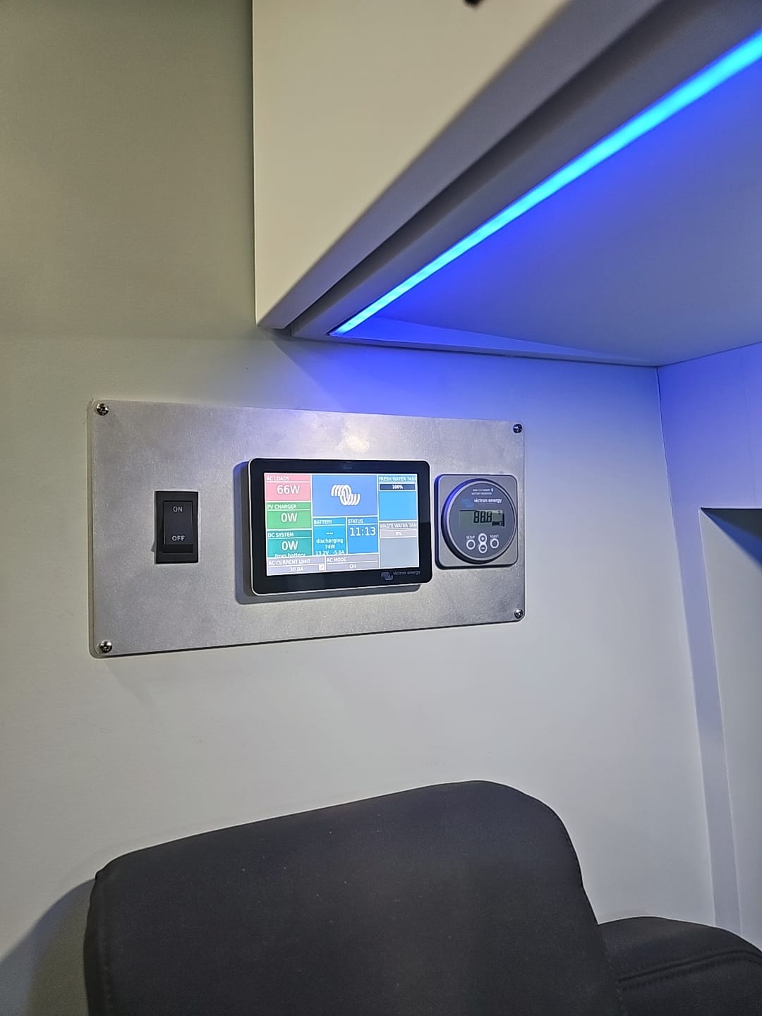 RV rental power management control panel. Displays 66W AC load, battery, and tank levels. Blue LED overhead.