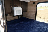 Inside an RV rental: a cozy bedroom with dark wood cabinets, a window AC unit, and a blue bed, ready for adventure.
