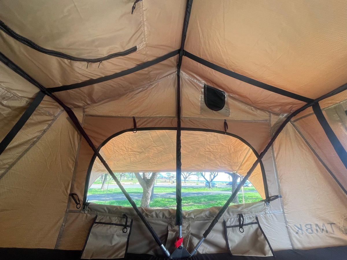 Inside an RV rental tent, looking out at the ocean, road, and trees from the campsite. Enjoy spacious outdoor living! — photo 5