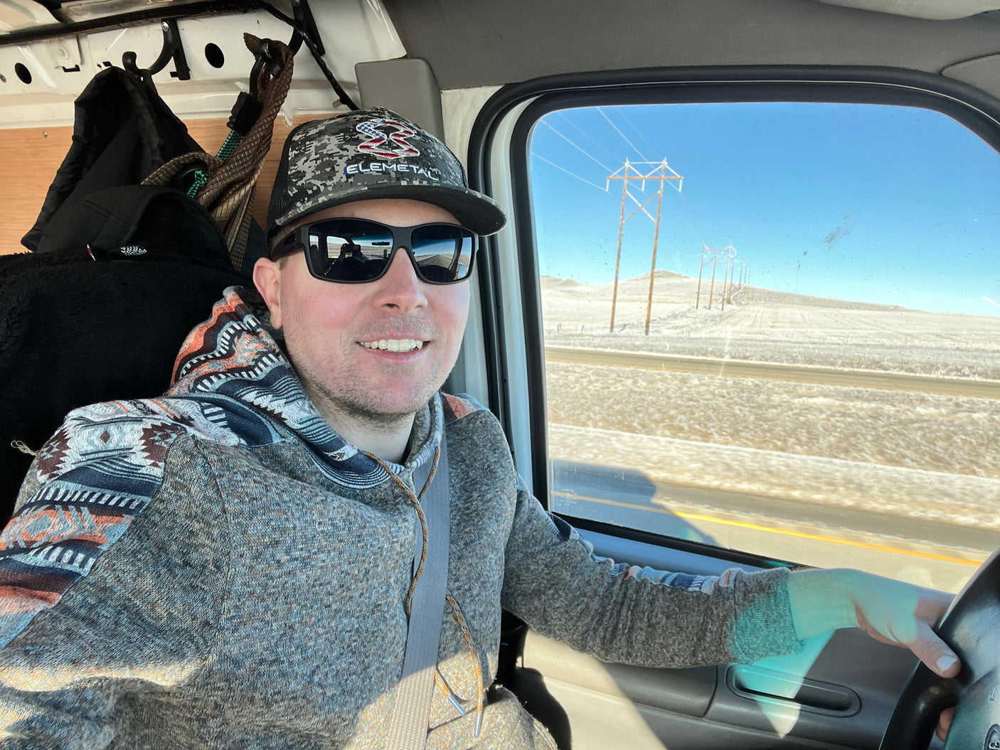 Man smiles driving an RV rental through a snowy landscape. Scenic road trip adventure.
