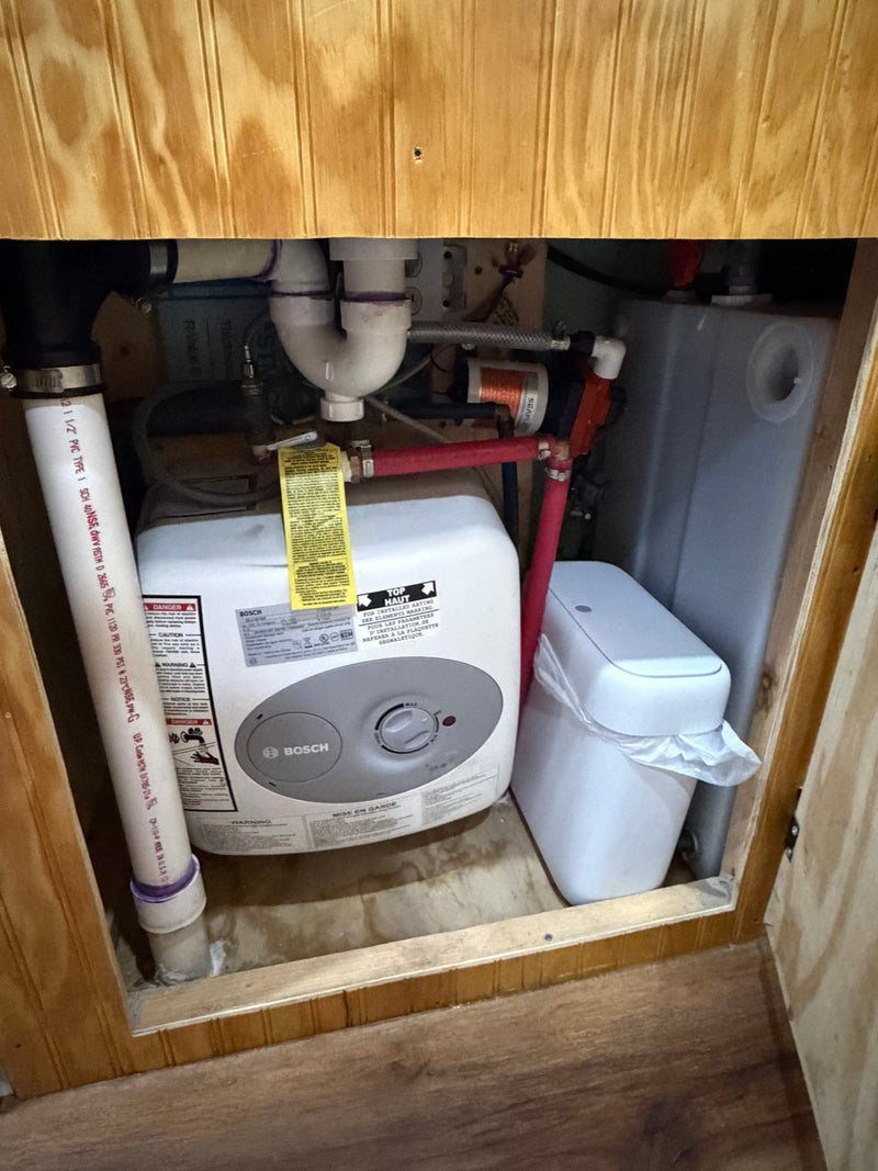 Essential RV rental plumbing: Bosch water heater, water pump, tank, and filtration system under the counter. — photo 8