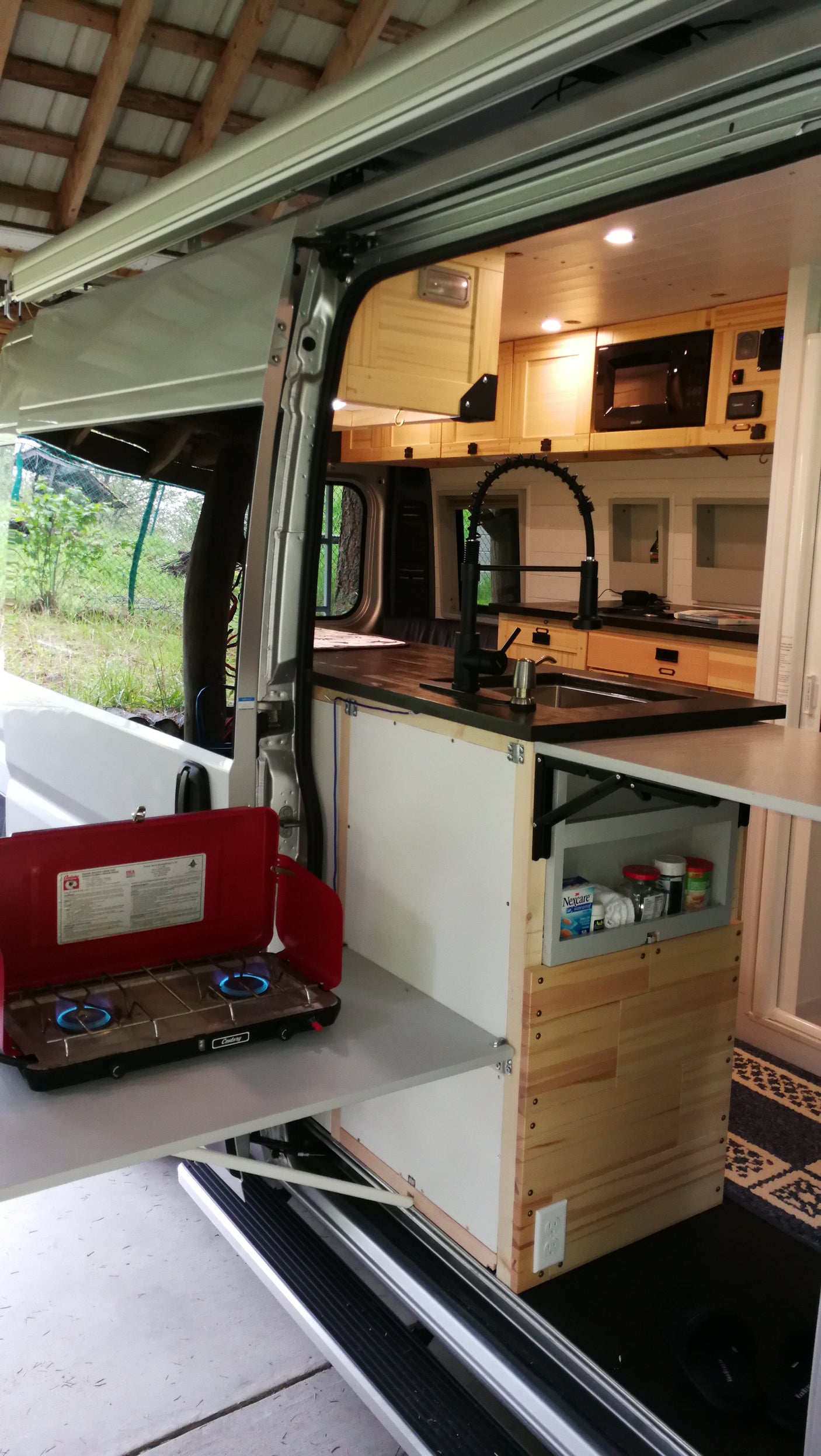 Compact RV rental kitchen with pull-out counter & portable stove for outdoor cooking, great for mobile adventures.