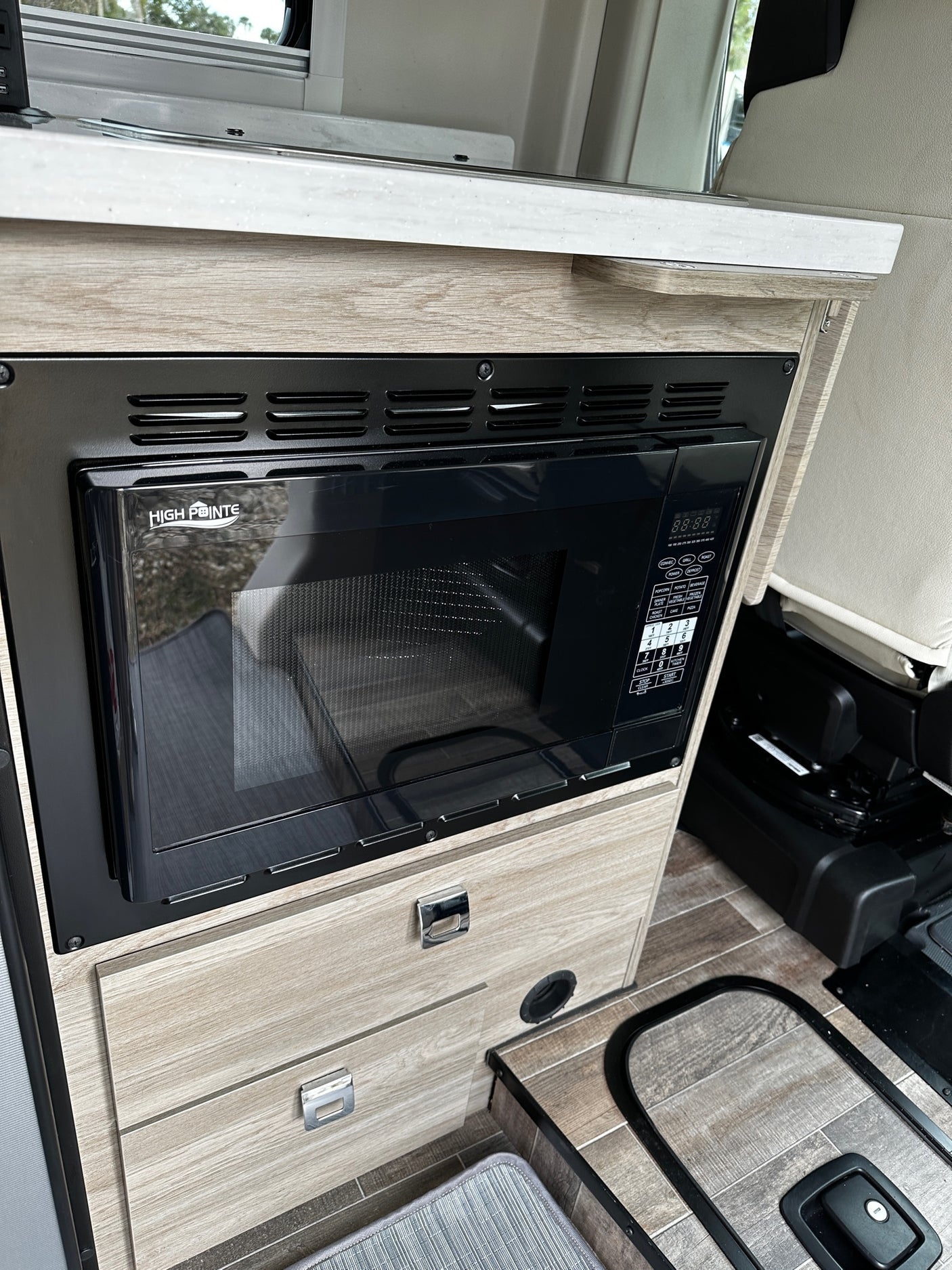 View of an RV rental kitchen: a built-in High Pointe microwave, wood-look counter, and flooring detail.