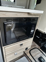 View of an RV rental kitchen: a built-in High Pointe microwave, wood-look counter, and flooring detail.
