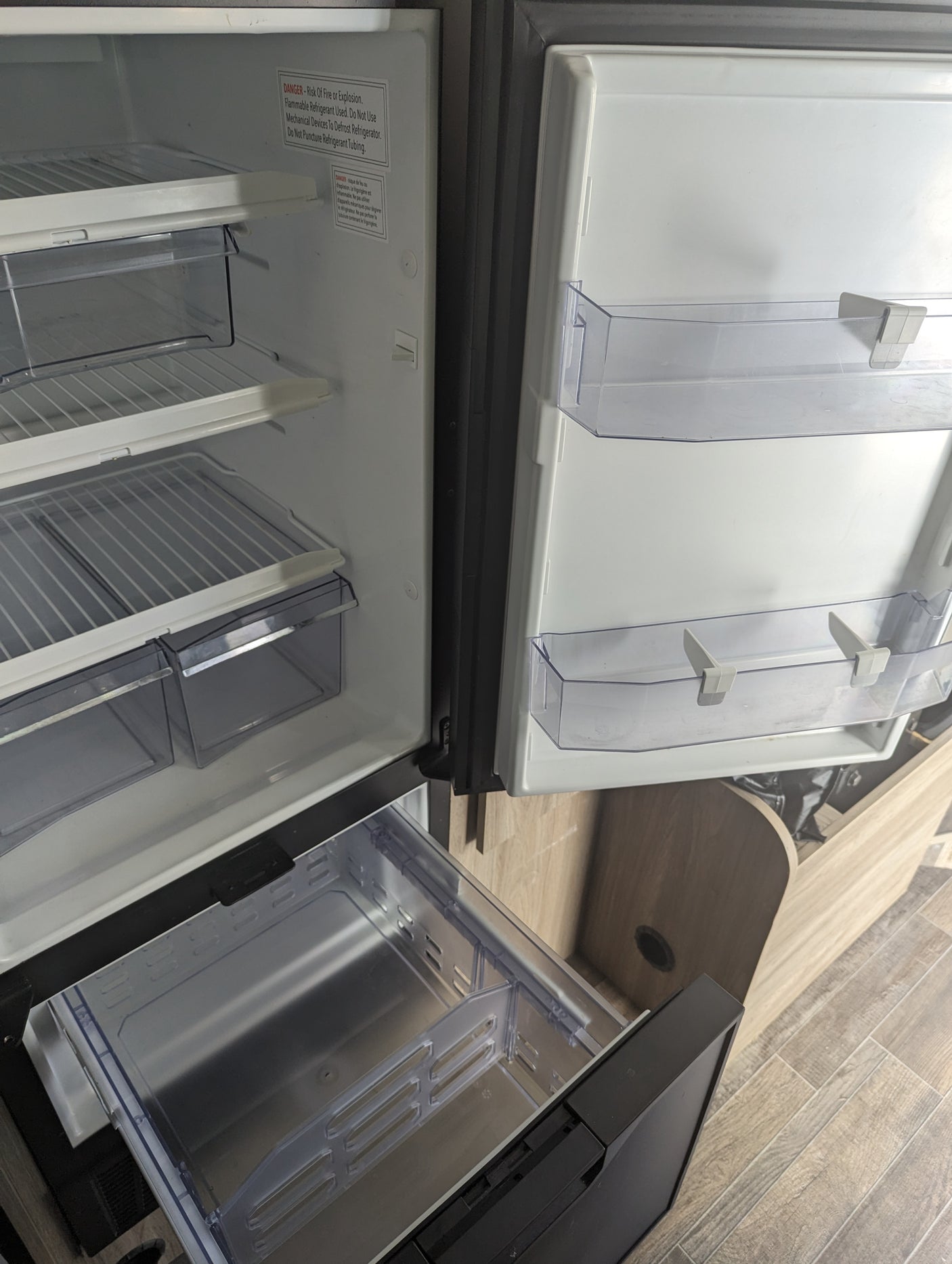 Clean, empty RV refrigerator interior in an rv rental, featuring shelves, crisper drawers, and door bins, ready for use.