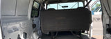 View of a white van's interior, showing bare walls and a dark bench seat, ideal for an RV rental.