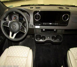 RV rental van's driver cockpit: Modern dashboard with a large screen, multi-function steering wheel, handy cup holders, and textured front seats.