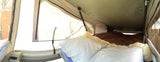 Cozy sleeping area inside an RV rental pop-up camper, featuring a bed with pillows and fabric walls.