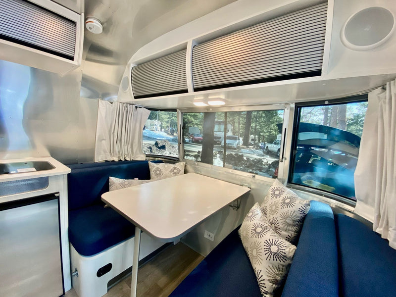  and cozy blue seating.|Cozy Airstream RV rental interior featuring a blue dinette — photo 5