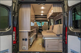 Spacious RV rental interior with light wood cabinetry, comfortable seating, and convertible bed, perfect for adventure travel.