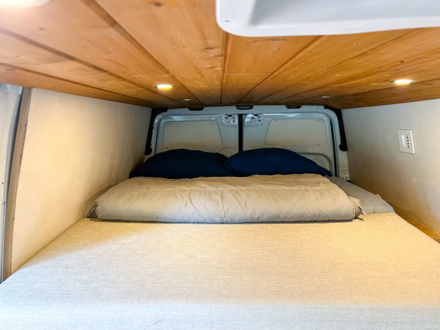 RV rental sleeping area featuring a comfortable mattress, soft bedding, a rustic wood ceiling, and warm recessed lights.