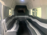 Spacious RV rental interior with black and gray luxury seating and a TV, perfect for group travel.