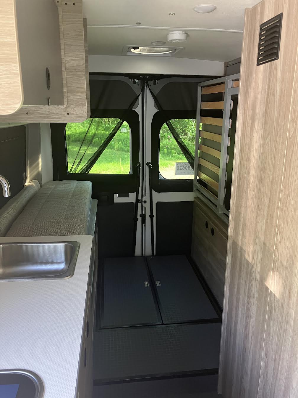 This RV rental features a camper van interior with a kitchenette, sink, and versatile bed/storage setup at the rear.