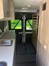 This RV rental features a camper van interior with a kitchenette, sink, and versatile bed/storage setup at the rear.