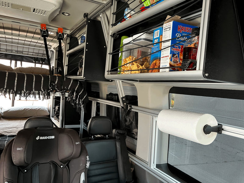 RV rental interior: bunk beds, child car seat, overhead shelving with groceries, and a paper towel holder. Designed for family travel. — photo 19