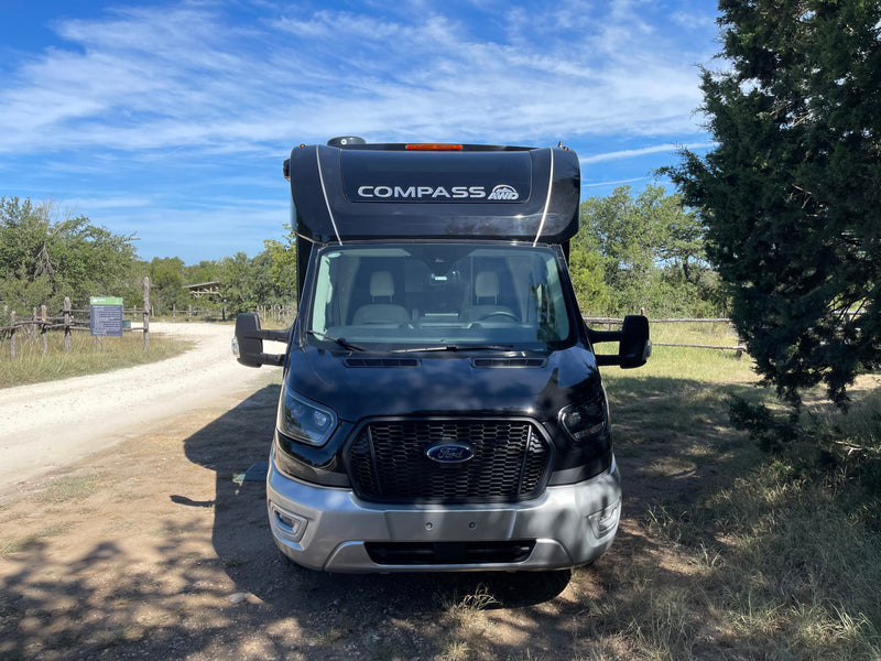 Front view of a black Ford Compass AWD RV rental on a dirt road at a park entrance, ready for an outdoor adventure. — photo 3