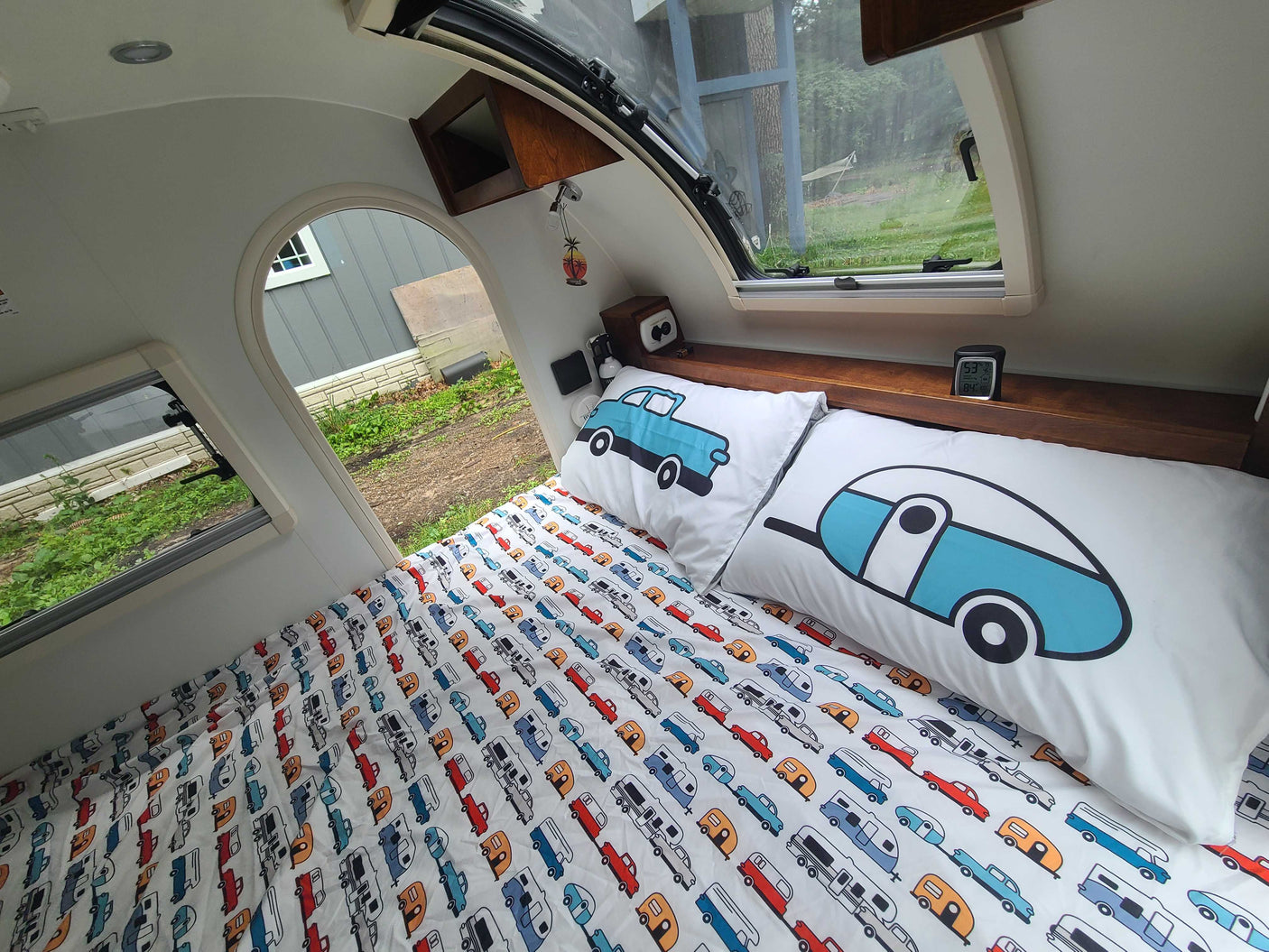 Cozy RV rental interior featuring a bed with playful car and camper bedding. Perfect for a mobile adventure.