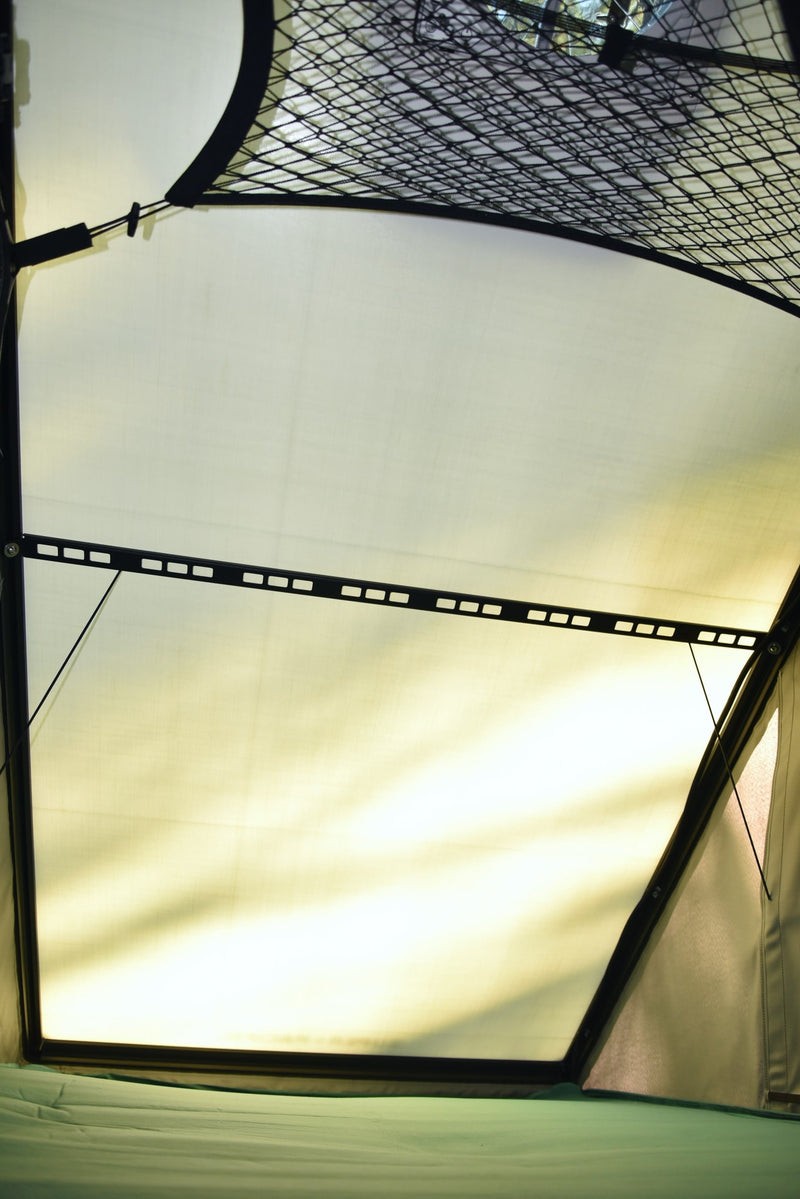 Interior of an RV rental pop-up tent, showing overhead mesh, bright translucent fabric walls, and a green sleeping pad. — photo 4