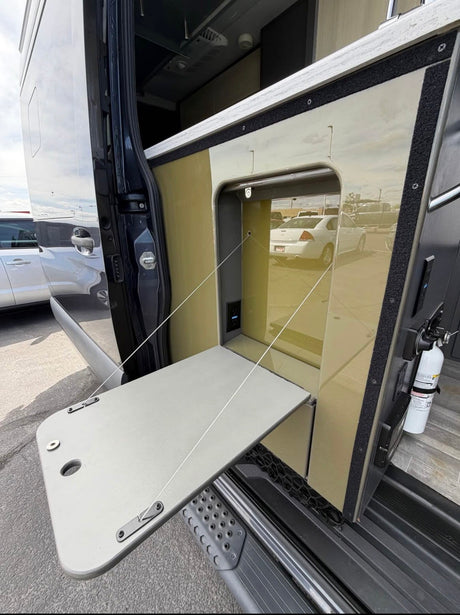 RV rental with side entry showing a fold-down table, USB/power port, and fire extinguisher for outdoor convenience.