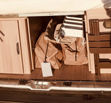 RV rental storage shows wooden cabinets, beige bags, a folded ladder, and brown camping chairs.